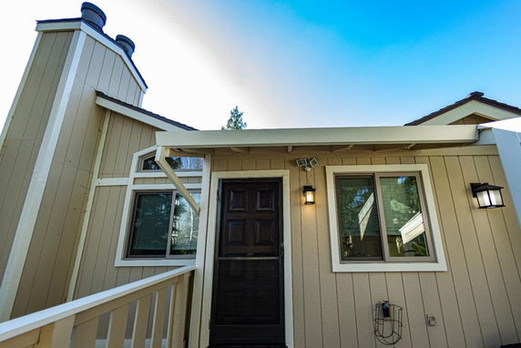 Front view of a house with beige siding and a dark wooden door.