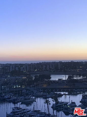 Panoramic view of a marina at twilight with boats and distant buildings.