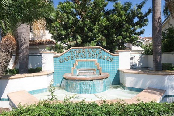 Front view of a building entrance with a decorative fountain and sign reading 'Torrance Gateway Estates'.