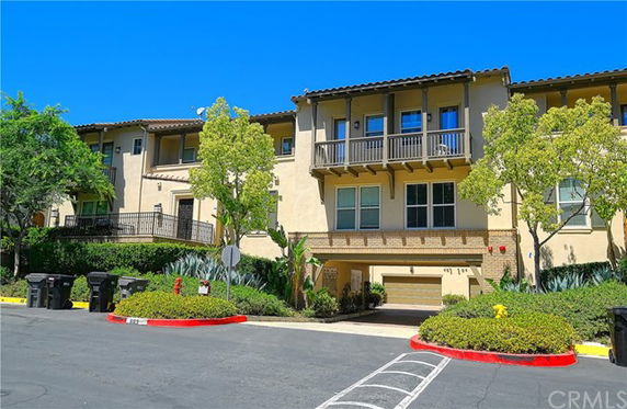 Front view of a multi-story residential building with balconies and garage underneath.
