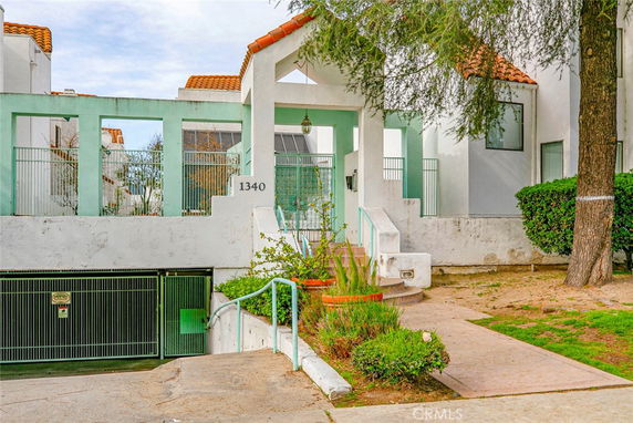Front view of a building with a staircase and gated entrance.
