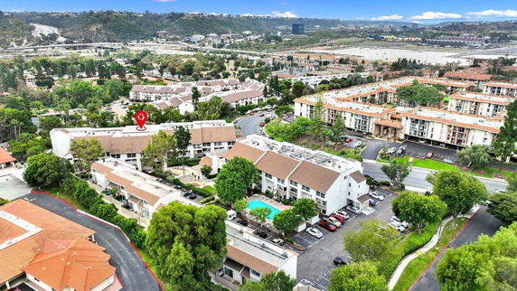 Panoramic view of apartment complexes surrounded by greenery and parking areas.