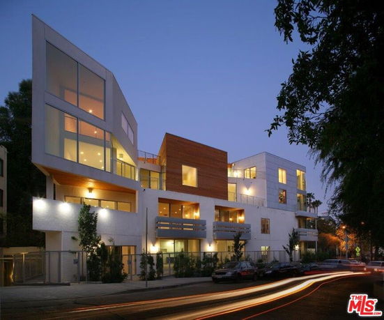 Front view of a modern multi-story building with large windows and wooden accents.