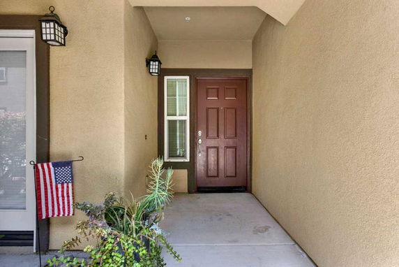 Front view of a house entrance with a brown door and beige walls.