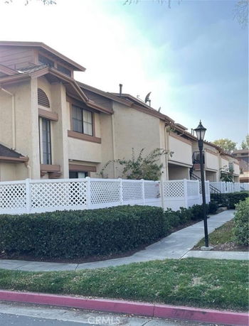 Front view of a multi-story townhouse with white fencing.