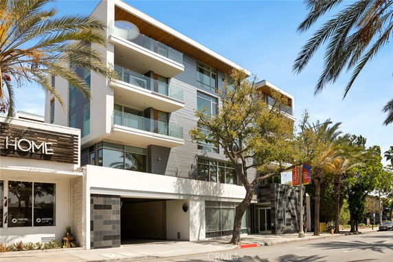 Front view of a modern multi-story building with balconies and large glass windows.