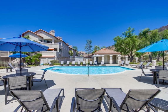 Outdoor swimming pool area with surrounding chairs and parasols.