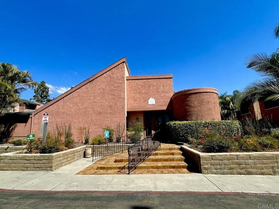 Front view of a modern building with a slanted roof and ramp access.