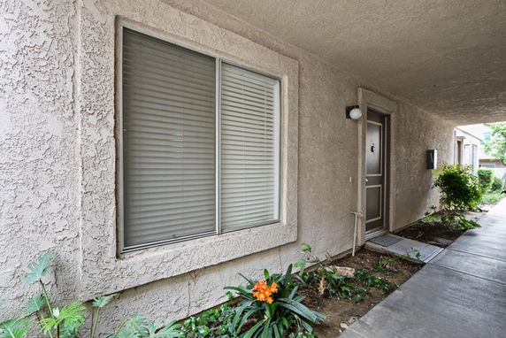 Front view of a building entrance with a window and a door in a covered outdoor corridor.