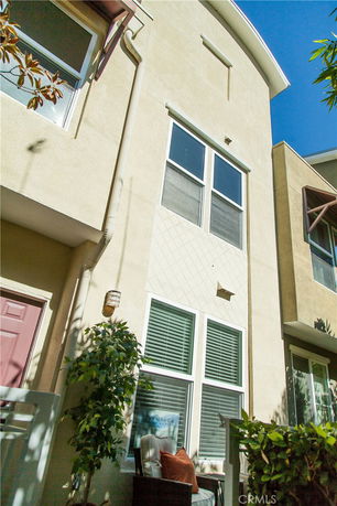 Front view of a multi-story building with large windows and a patio area.
