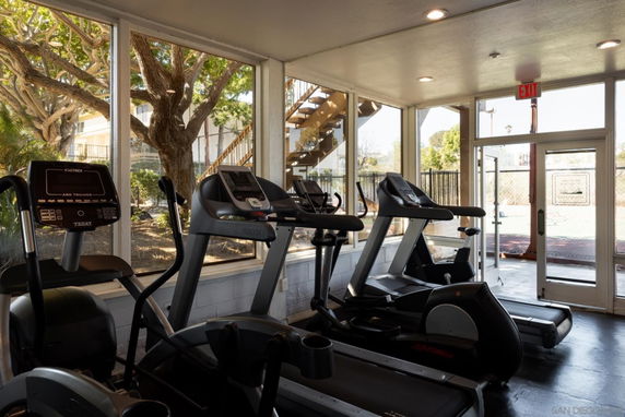 Indoor gym area with exercise machines and large windows.