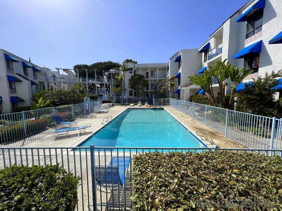 Outdoor swimming pool surrounded by apartment buildings with balconies.