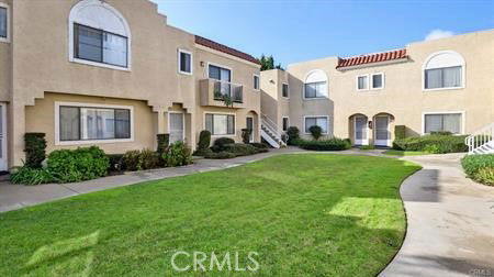 Front view of a multi-story apartment complex with beige stucco exterior and arched windows.