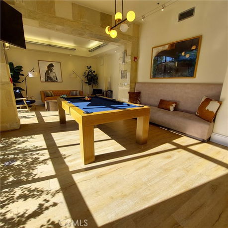 Recreation area with a billiards table and seating in a well-lit room.