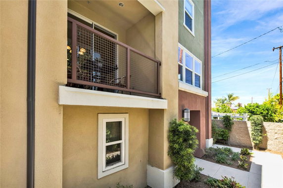 Partial view of a multi-story house with a balcony and multiple windows.