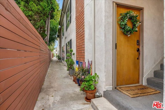 Side view of a residential building with a narrow walkway and a wooden door.