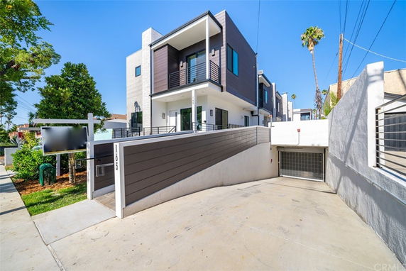 Front view of a modern multi-story building with a driveway leading to underground parking.