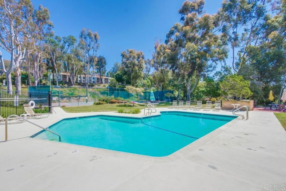 Outdoor swimming pool area with surrounding trees and lounge chairs.