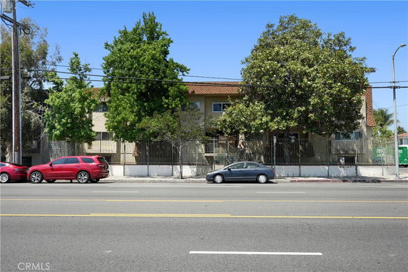 Front view of a two-story building with a brown roof and surrounding trees.
