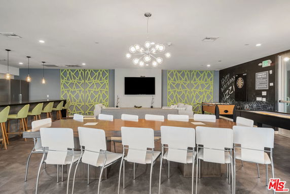 Recreation room with a long table, chairs, bar area, and games.