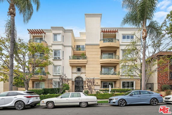 Front view of a multi-story residential building with balconies and a central entryway.