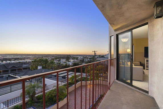 View from a balcony overlooking a residential area and distant landscape.