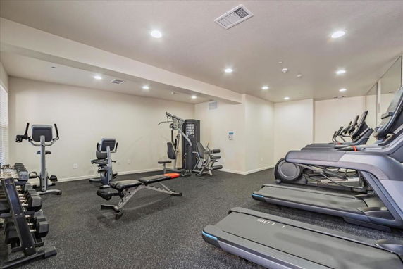 Indoor gym area with exercise equipment including treadmills, bicycles, and weights.