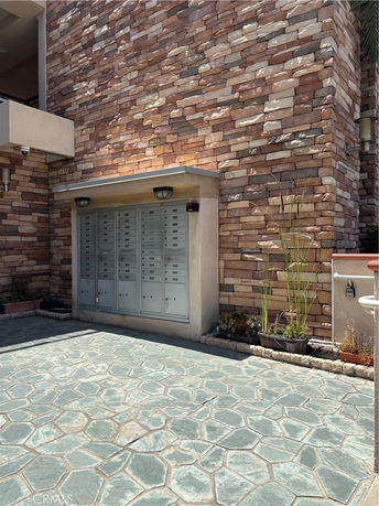 Front view of a building with stone wall and multiple mailboxes.