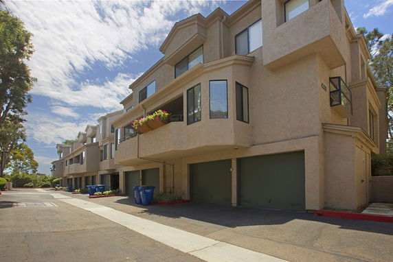 Front view of a multi-story building with garages and large windows.