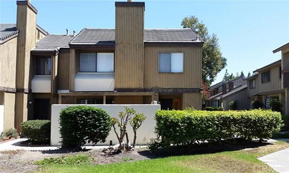 Front view of a two-story house with vertical wooden paneling and a chimney.