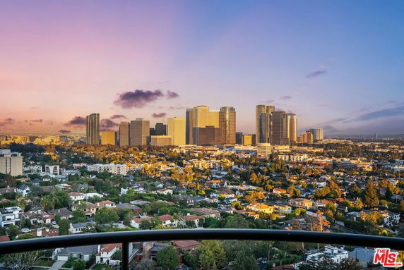 Panoramic view of a cityscape with tall buildings and residential areas at sunset.