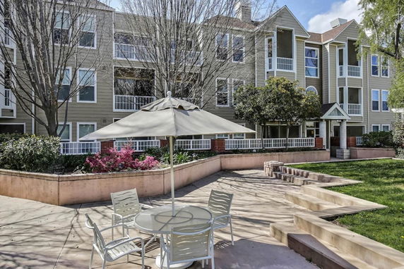 Front view of a multi-story residential building with balconies and a landscaped foreground.