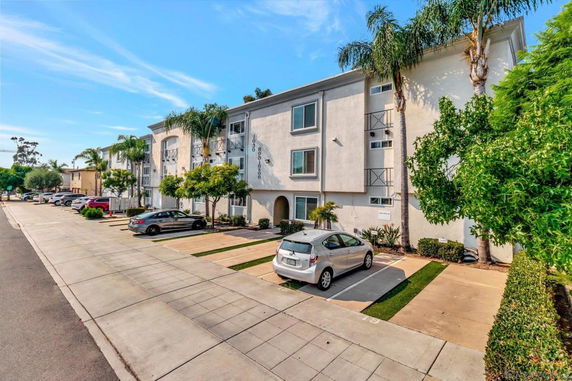Front view of a multi-story residential building with parking area.