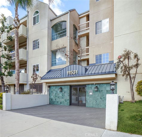 Front view of a multi-story residential building with balconies and an entrance canopy.