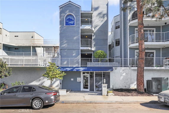 Front view of a multi-story apartment building with balconies and a central entrance.