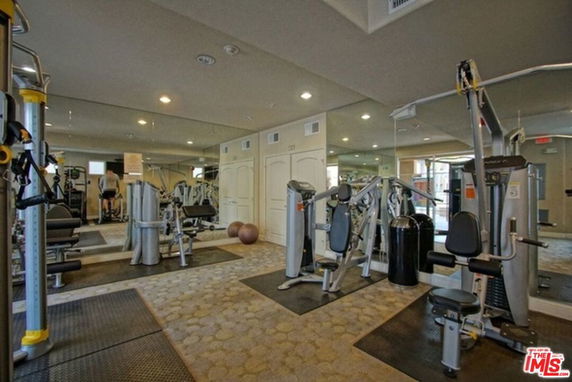 Indoor gym area with various exercise machines and mirrored walls.
