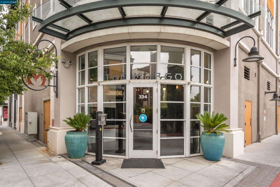 Front view of a building entrance with a curved glass canopy and large windows.