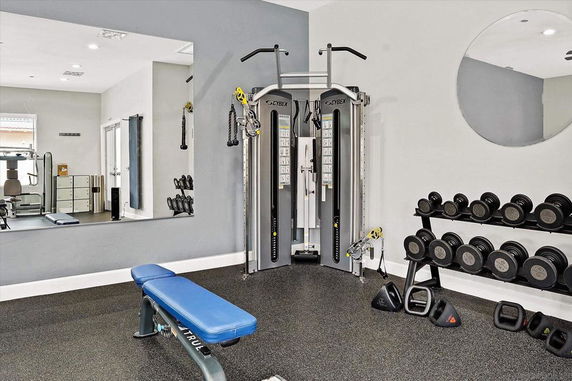Indoor gym area equipped with exercise machines and dumbbells.