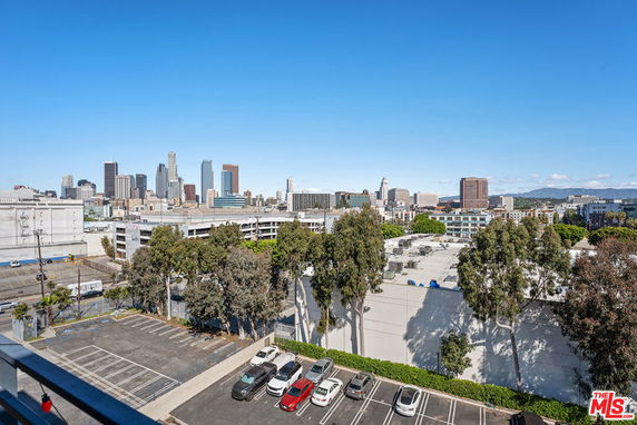 Panoramic view of a city skyline with buildings and parking area in foreground.