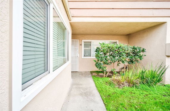 Front view of a house entrance with windows and a small garden area.