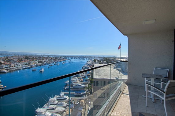 View from a balcony overlooking a marina with boats and a distant coastline.