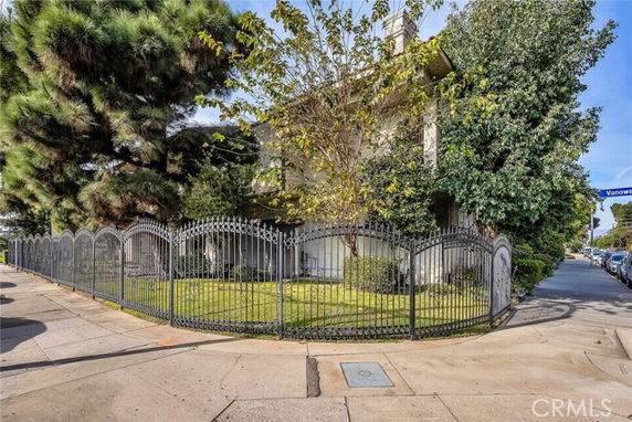 Front view of a house with a wrought iron fence and trees surrounding the property.