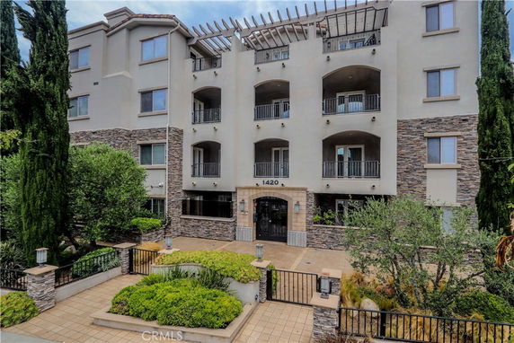 Front view of a multi-story building with balconies and a gated entrance.
