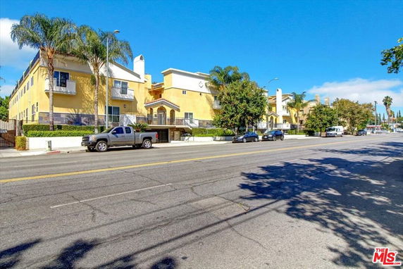 Front view of a multi-story building with a driveway and parked cars.