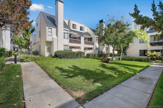 Front view of a multi-story residential building with balconies and chimneys.
