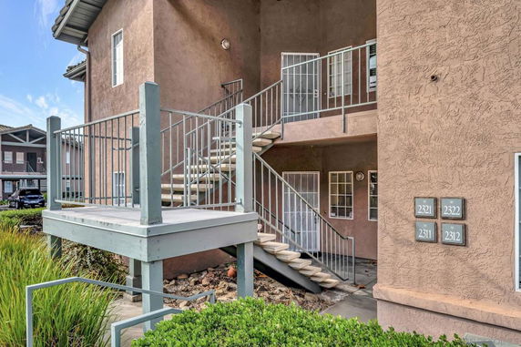Front view of a multi-story building with external staircase and multiple entry doors.