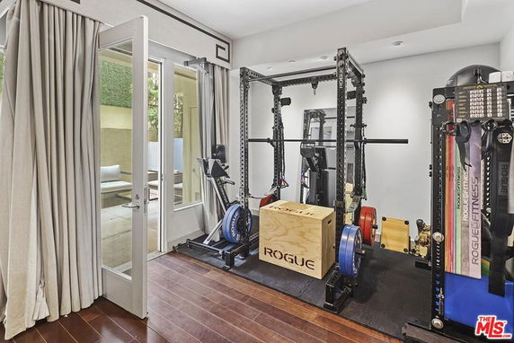 Indoor gym area with exercise equipment and wooden flooring.