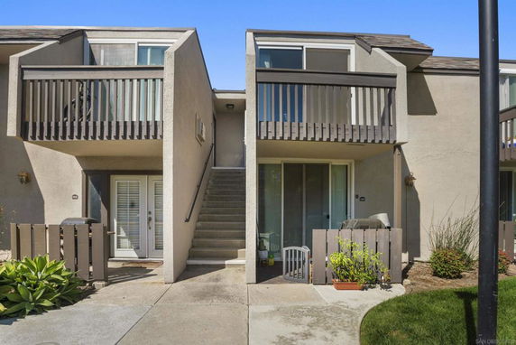 Front view of a two-story residential building with balconies and stairs.
