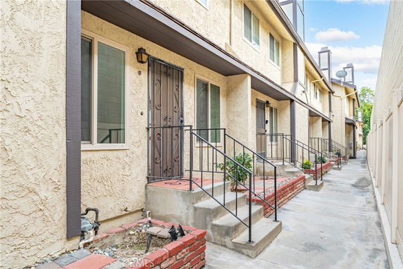 Front view of a multi-story townhouse complex with stairs leading to each entrance.
