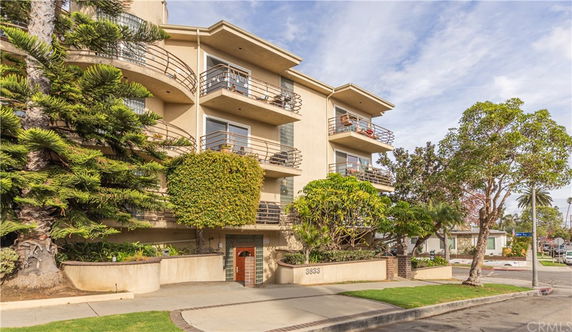 Front view of a multi-story residential building with balconies and greenery.